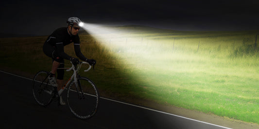 Cyclist riding at night with a powerful wide-beam headlamp illuminating the entire road